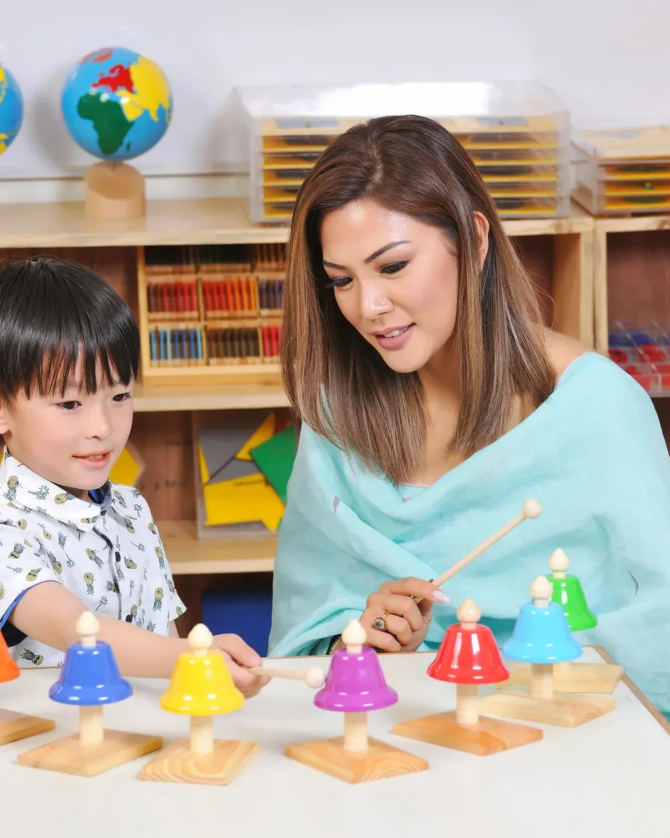 Montessori teacher guiding a young child with the musical bells