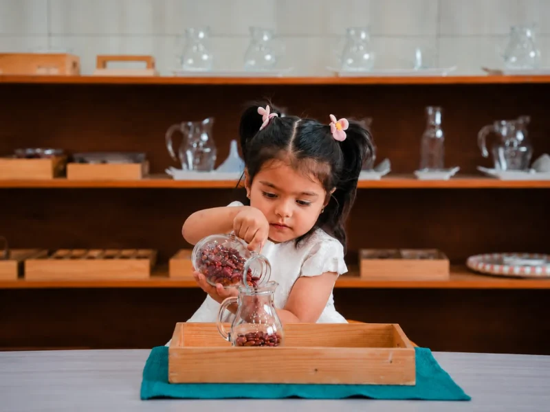 Girl pouring beans into a glass jar