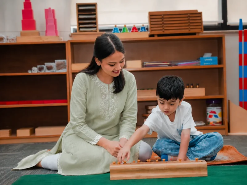 Teacher presenting a wooden material to a boy on a mat