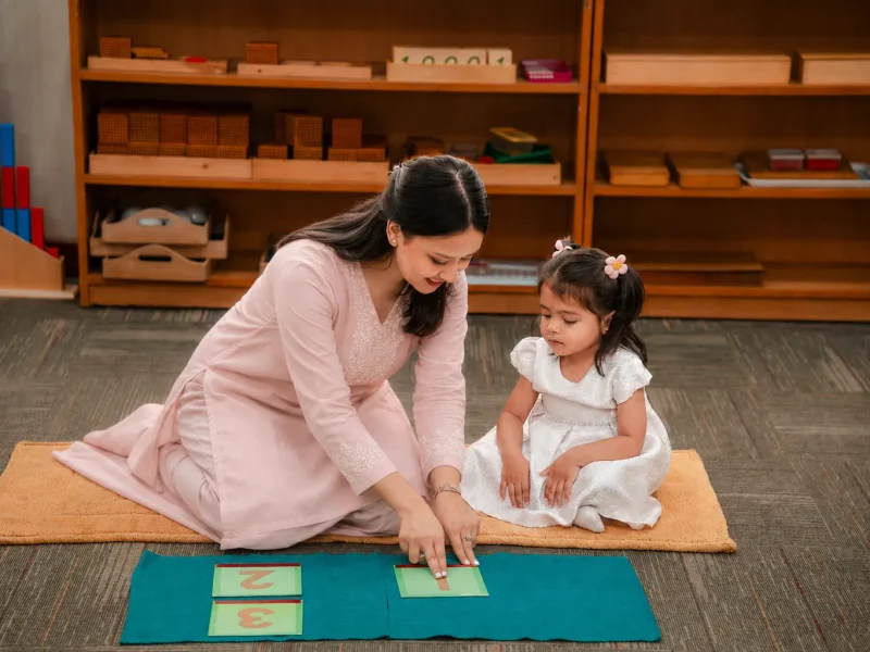 Teacher guiding a child with picture cards on the floor