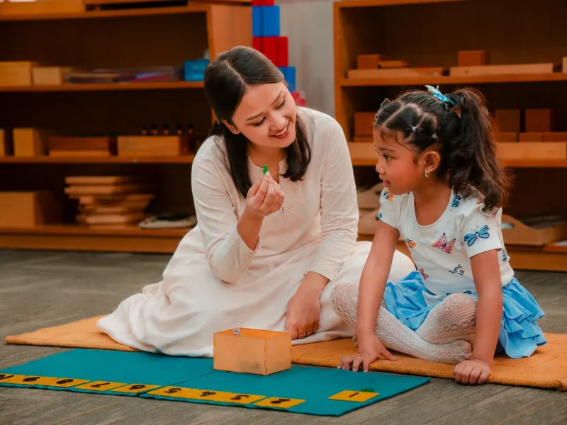 Teacher showing a child a small object from a wooden box